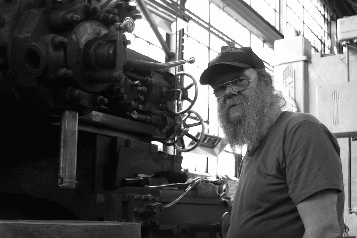 factory worker standing by heavy equipment